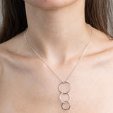 Sterling Silver Necklace with Drop Pendent of 3 indvidual circles that interconnect with the middle circle, giving a drop effect.  Circles have the hammered textured applied.  Worn on a model.