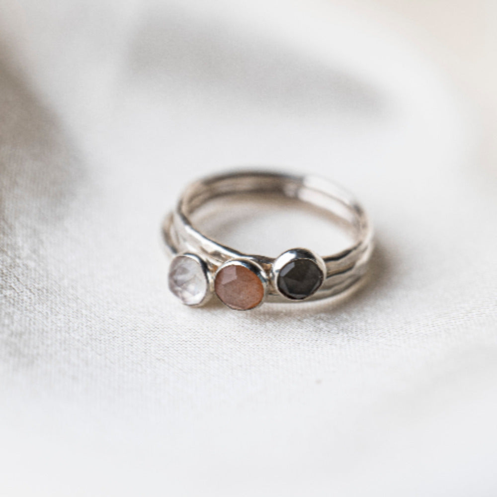 3 Moonstone Gemstone Rings: Grey Moonstone, Peach Moonstone and Rainbow Moonstone.  Set on Hammered Tesxtured Sterling Silver Rings.  Displayd on a cream silk background.