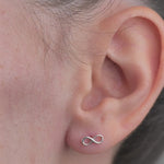 Sterling Silver Infinity shaped Earrings worn in models ear.