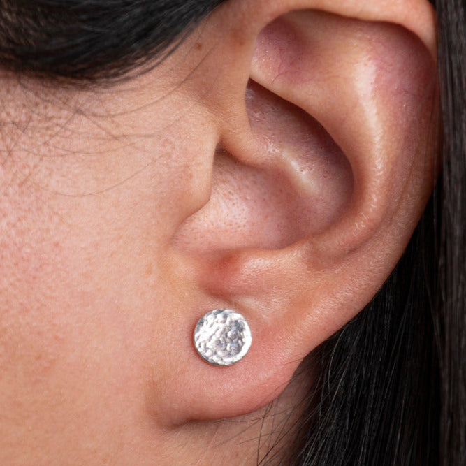 Sterling Silver Round shaped Hammered Textured Earrings worn on models ear lobe