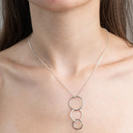 Sterling Silver Necklace with Drop Pendent of 3 indvidual circles that interconnect with the middle circle, giving a drop effect.  Circles have the hammered textured applied.  Worn on a model.
