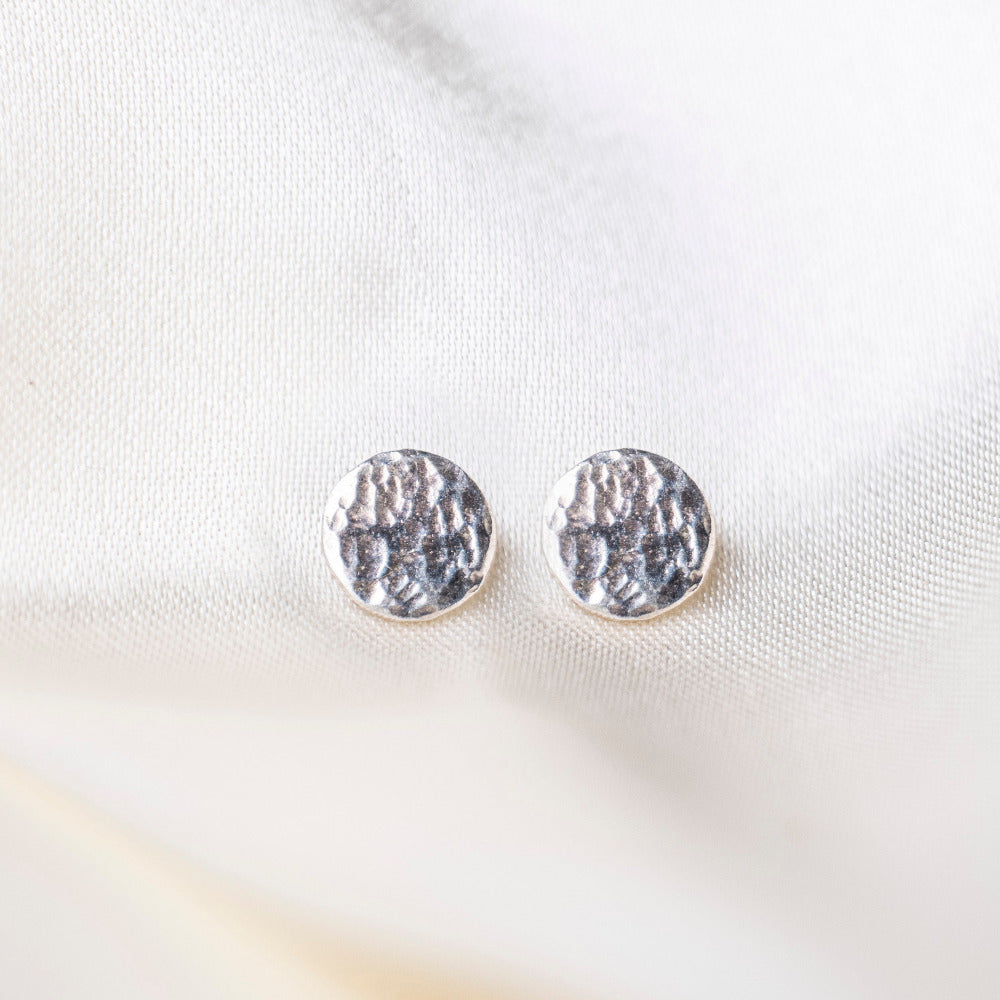 Round Hammered Earrings on silk background 
