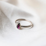 Rhodolite Garnet Gemstone Pear shaped Sterloing Silver Ring worn on silk background 