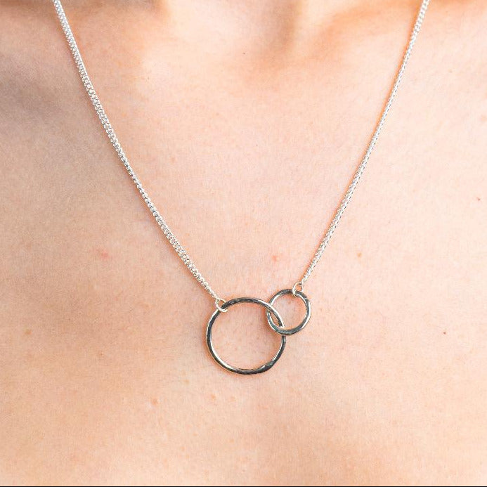 Sterling Silver Necklace with two interlocking circles.  One circle bigger then the other. Both circles textured with the hammered effect.