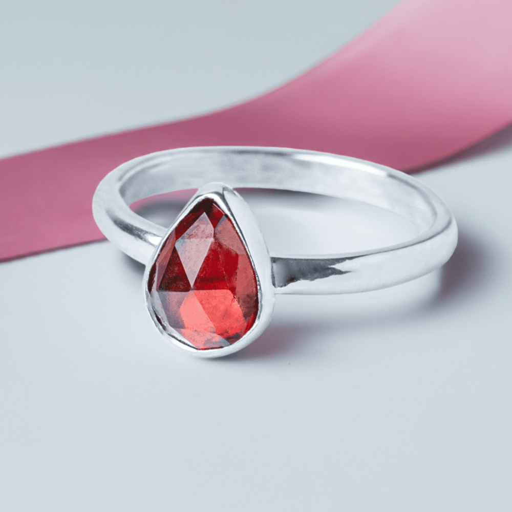 Handmade Sterling Silver Garnet Pear Gemstone Ring on a pink ribbon background