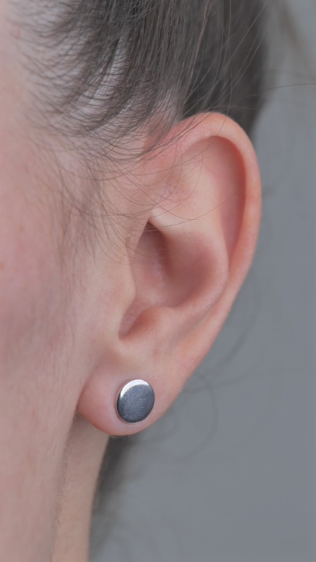 Sterling Silver solid shaped circle earrings, worn in models ear.