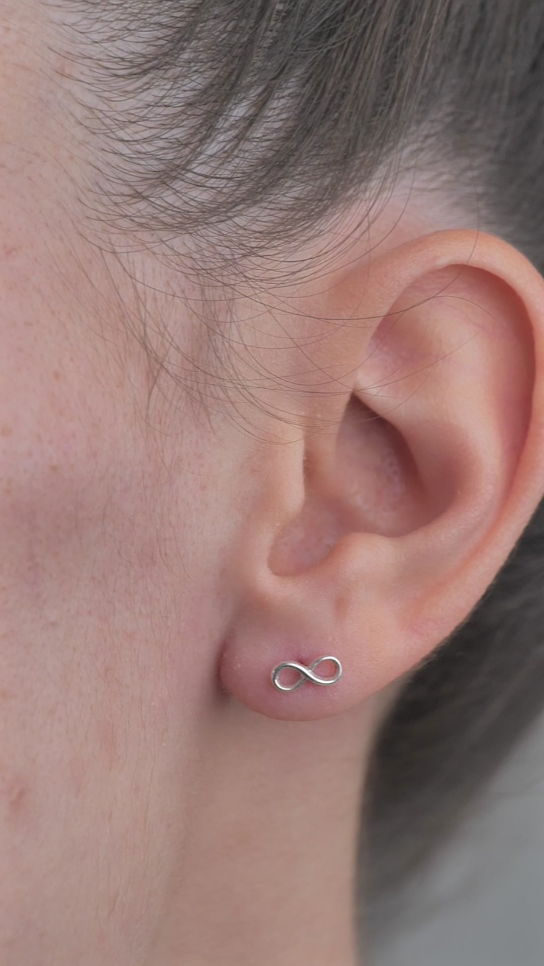 Sterling Silver Infinity shaped Earrings worn in models ear.