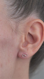 Sterling Silver Infinity shaped Earrings worn in models ear.