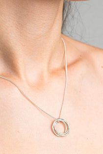 Sterling Silver Necklace with a intertwined Russian Ring Style pendent with a Hammered texture. Worn on a model with side profile.