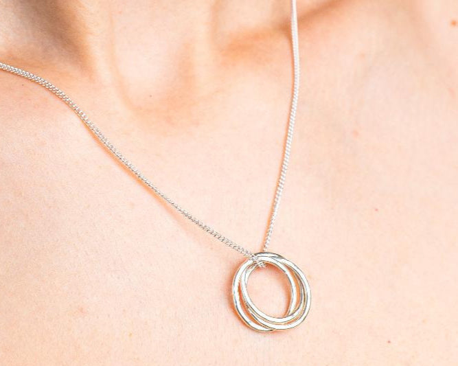 Sterling Silver Necklace with a intertwined Russian Ring Style pendent with a Hammered texture. Worn on a model with side profile.
